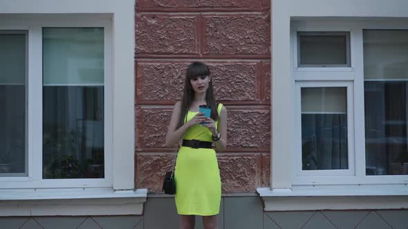 Stylish Young Lady in Light Green Dress Drinks Beverage in Cup on Street