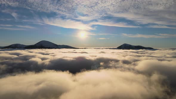 Aerial view of vibrant sunrise over white dense fog with distant dark peaks of Carpathian