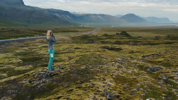 Woman Traveler on Lava Field of Berserkjahraun Photographing Costline Iceland