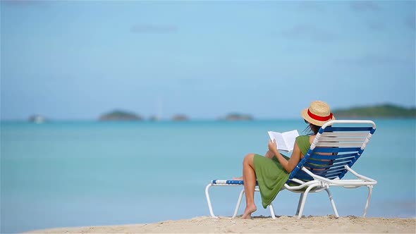 Young Woman Reading Book on Sunbeds During Tropical White Beach