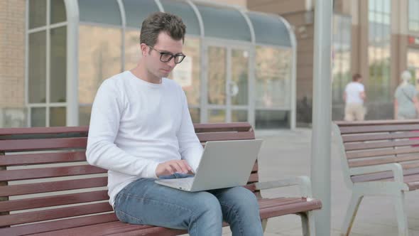 Young Man Leaving Bench After Closing Laptop