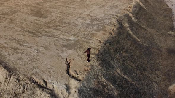 Beautiful aerial view of a drone, a happy woman dancing on the edge of a cliff with an ocean view.