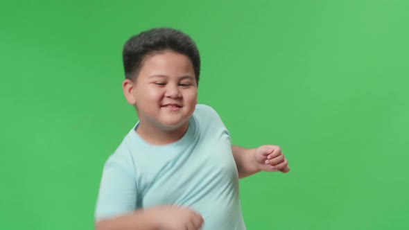 The Smiling Asian Little Boy Dancing In A Green Screen Studio