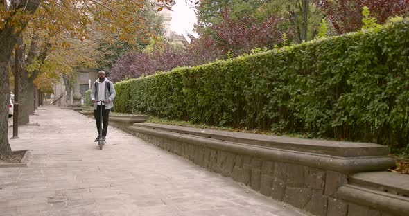 A Young Man Rides an Electric Scooter on the Street