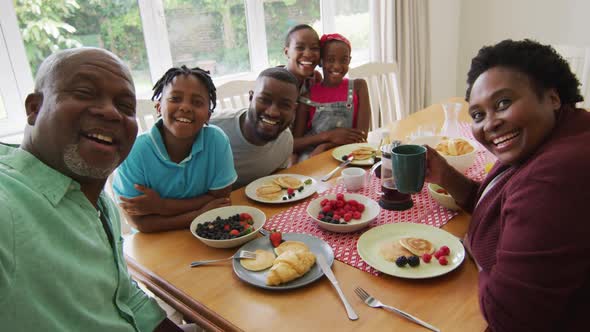 Three generation african american family taking a selfie while having breakfast together at home