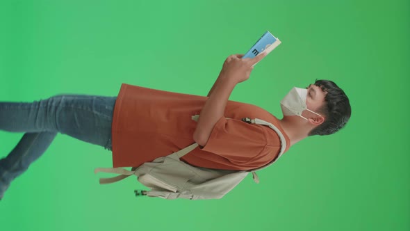 Asian Boy Student Wearing A Mask, Reading A Book While Walking To School On Green Screen