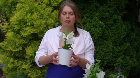 Happy Confident Woman Admiring White Flower in Pot Smelling Plant in Slow Motion Smiling