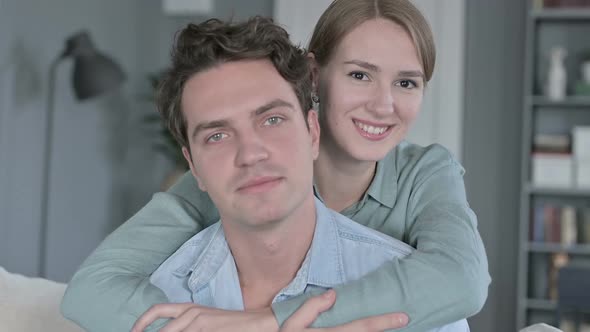 Portrait of Cheerful Woman Hugging Man From the Back and Smiling at the Camera