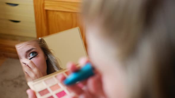 Young woman applying mascara on eyelashes