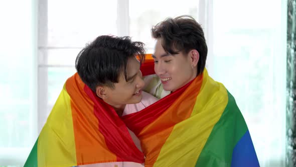 Portrait of Happy Asian gay couple embracing and showing their love under lgbt colorful rainbow flag