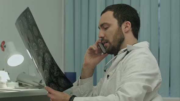 Male Doctor Talking on Cellphone at Modern Hospital Indoors