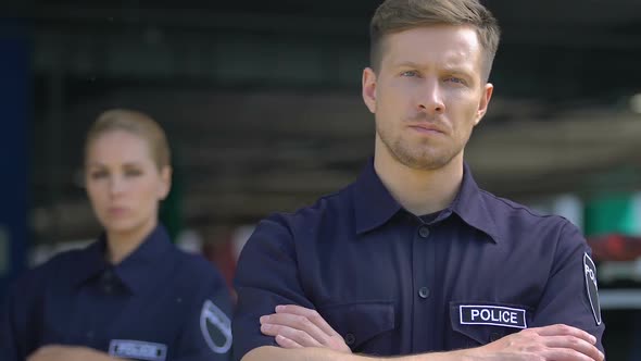 Young Male and Female Cops Looking Seriously Into Camera