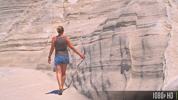 Woman hand touching eroded rock formation at Sarakiniko beach, Milos, Greece