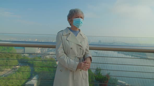Senior Woman Putting Off Medical Mask and Taking Deep Breath Outdoors