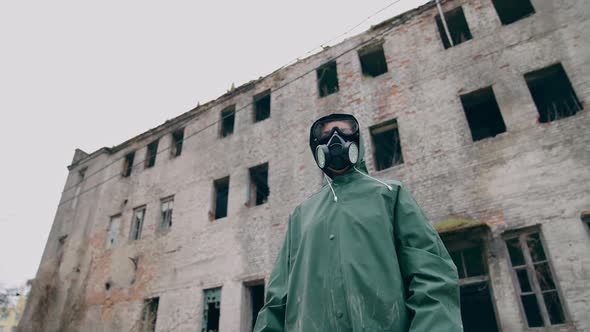 Man in gas mask near abandoned destroyed building