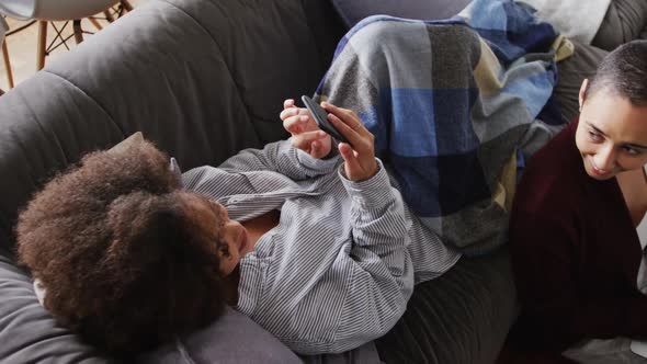 Lesbian couple using laptop and mobile phone in living room