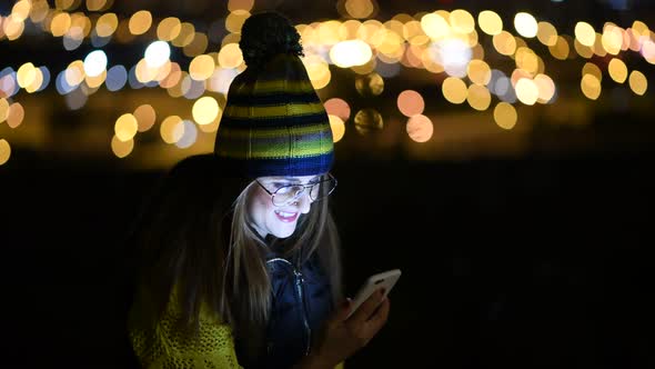 Woman checking phone at night with city lights as background