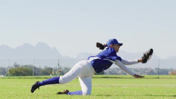 Caucasian female baseball player, fielder catching and diving with ball on baseball field