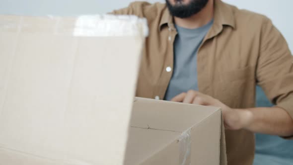 Closeup of Male Hands Opening Cardboard Box Unpacking Things During Relocation