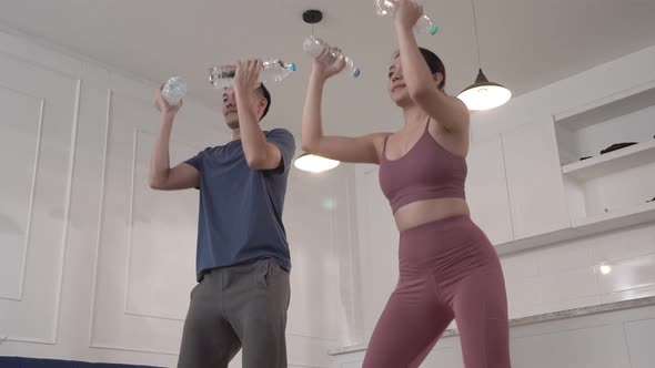 Asian couple using water bottle as dumbbell for exercise