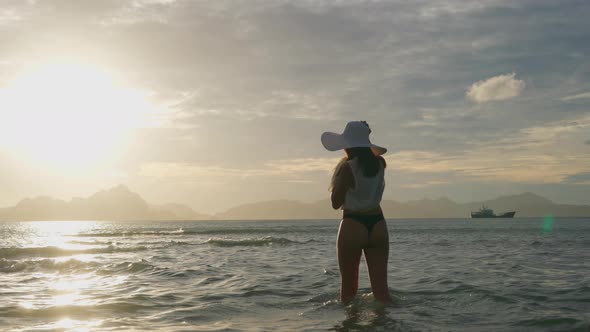 Woman In Thong And Sun Hat Watching Sun Set