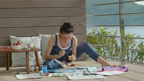 Young American Woman is Engaged in Creativity Using Paints While Sitting at Home Terrace Rbbro