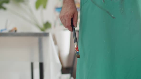 Closeup of man hand holding brush and then raising or lowering arm. Male artist holds brush in hand