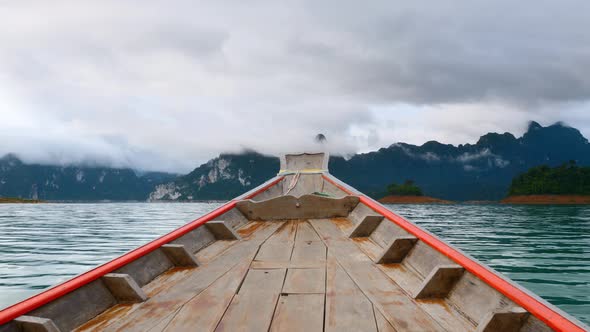 Wooden Boat Sailing on Morning Blue Lake with Limestone Mountains in Mist