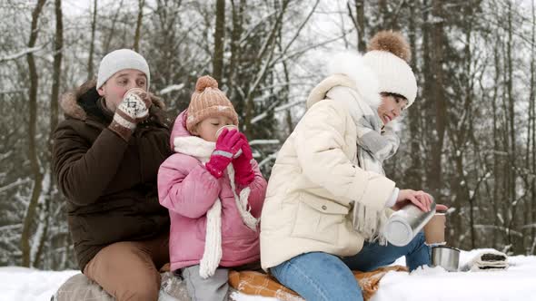 Family Drinking Tea in Winter Forest