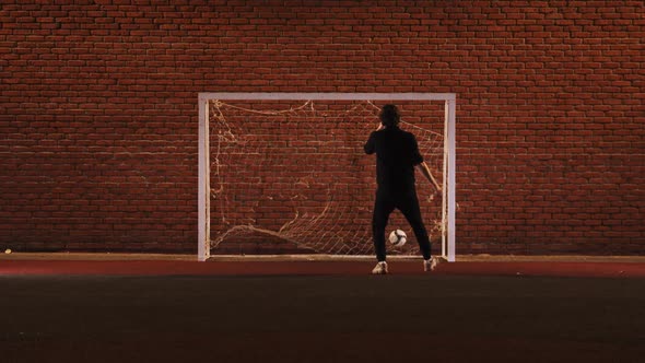Young Man Playing Football on the Playground - Kicking Ball in Gates alt