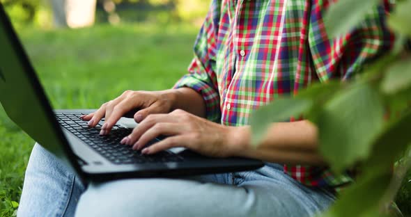 Woman Freelancer in Casual Clothes with Her Computer Laptop Sitting on the Grass at the Park