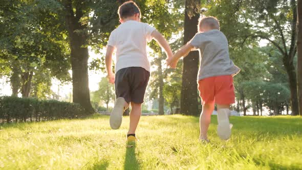 Two Young Boys Running in a Park and One Boy Stumbles on the Ground, Gimbal Follow Shot, Running Awa