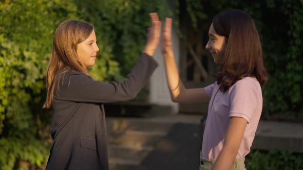 Side View Two Happy Teenage Girls Gesturing Highfive in Slow Motion at Golden Sunset in Park