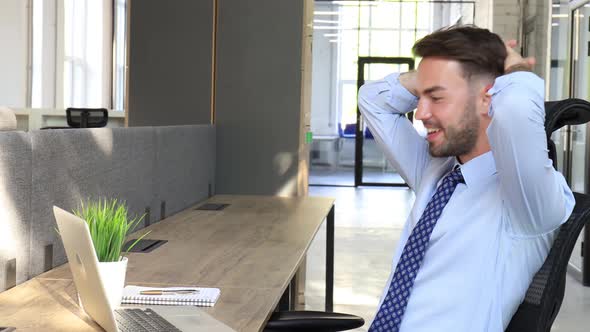 Businessman feels overjoyed looks at laptop. Happy man reads good news using laptop