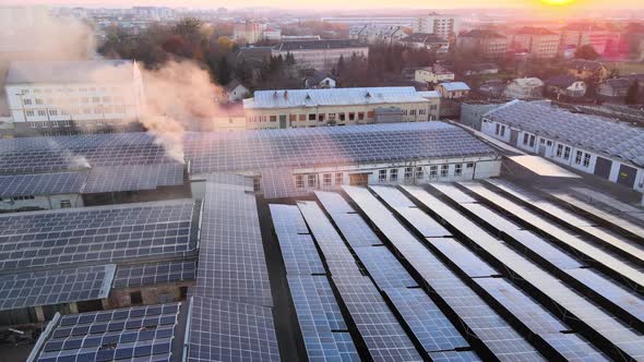 Aerial View of Blue Photovoltaic Solar Panels Mounted on Industrial Building Roof for Producing