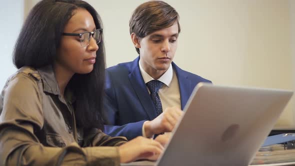 Male Lawyer Explaining Contract Detail To African-american Colleague in Office