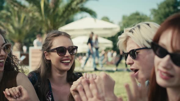 Group of friends sitting together on the grass and dancing at music festival. Shot with RED helium c