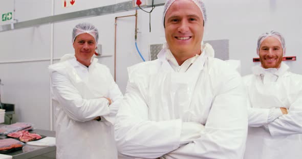 Team of smiling butcher standing with arms crossed