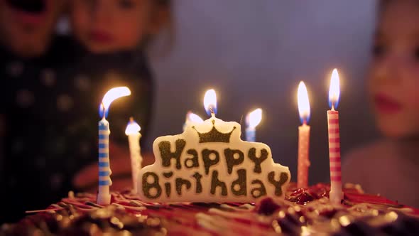 Father with Children Blowing Candles on a Birthday Cake.