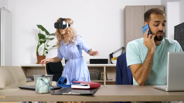 Beautiful Blonde Woman Explores Virtual Reality While Her Partner Is Talking on the Cellphone