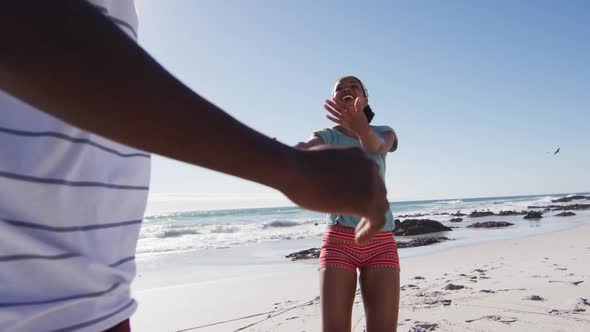 African american couple smiling, holding hands and running on the beach