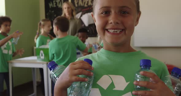 Girl wearing recycle symbol tshirt holding plastic bottles alt