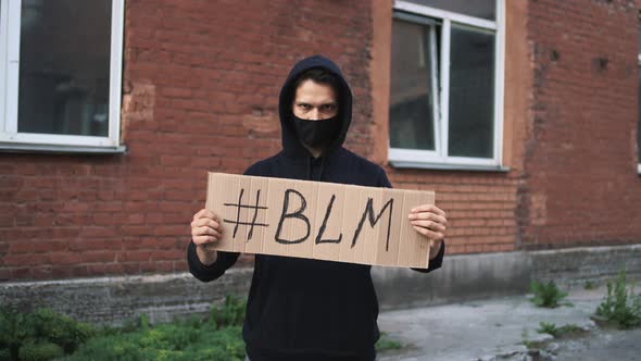 Man in Mask Stands with Cardboard Poster in Hands  BLACK LIVES MATTER