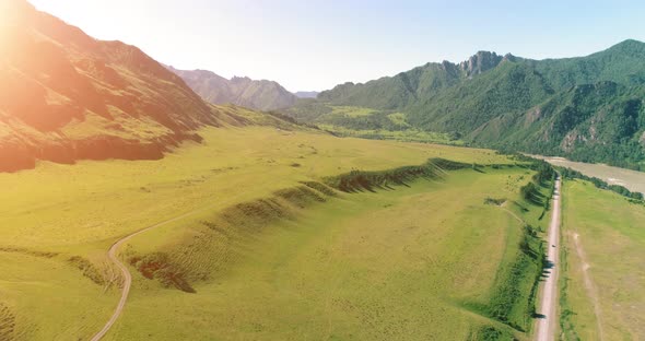 Aerial Rural Mountain Road and Meadow at Sunny Summer Morning. Asphalt Highway and River.