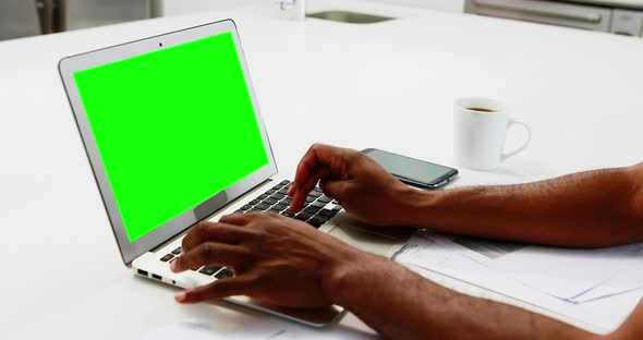 Man using laptop in kitchen 4k