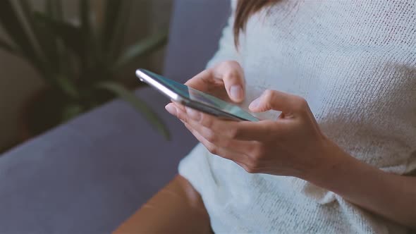 Woman Using Mobile Phone Sitting on the Couch