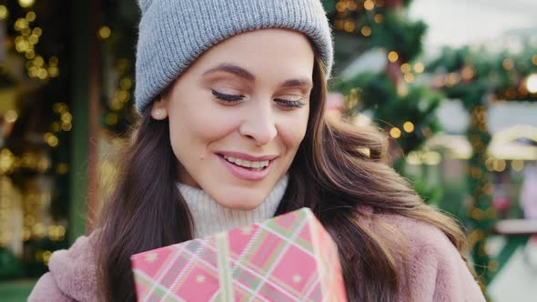 Handheld view of woman opening Christmas gift. Shot with RED helium camera in 8K.  