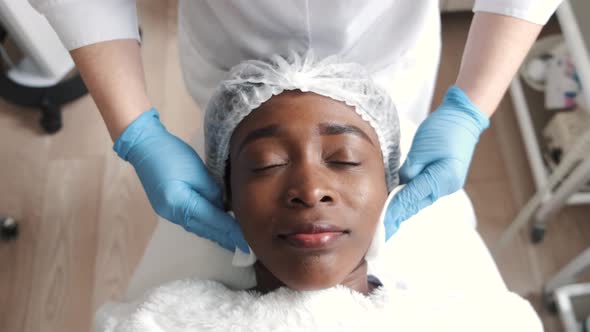 Cosmetologist Doing Facial Massage Manually to African Client