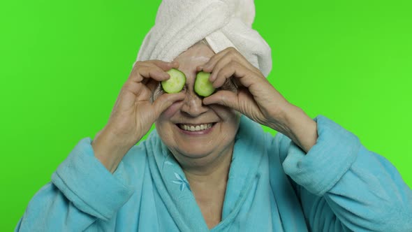 Elderly Grandmother in Bathrobe After Shower. Old Woman with Slices of Cucumber