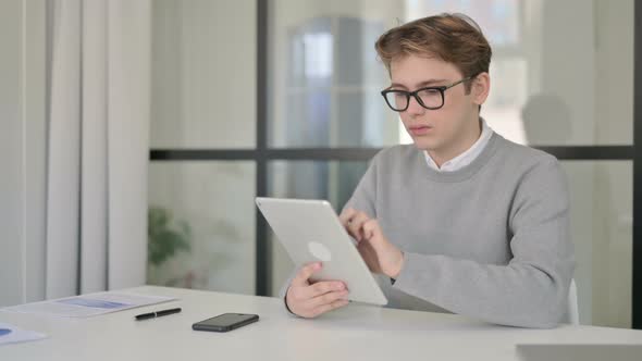Young Man Using Tablet While Sitting in Modern Office